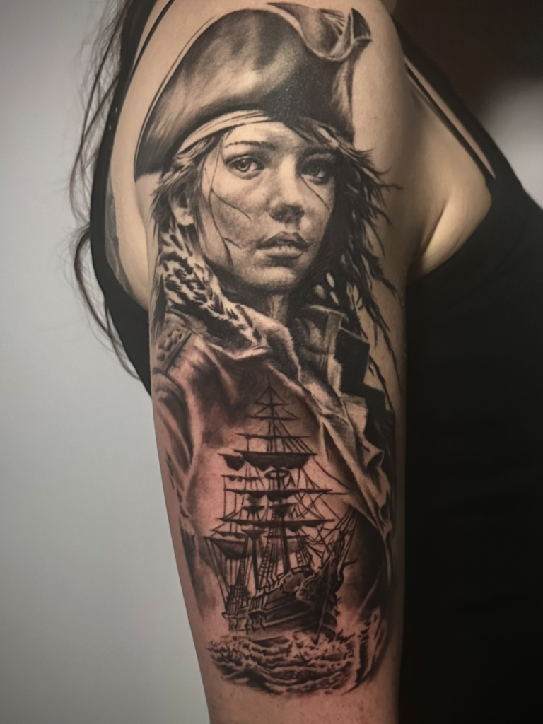 Detailreiche Tätowierung einer Frau im Piratenlook mit Schiff im Hintergrund.marburg tattoo, tattoo marburg, tattoo studio marburg