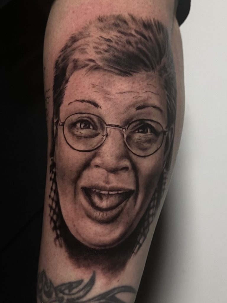 Tattoo eines lächelnden Gesichts mit Brille und kurzem Haar auf einem Unterarm.marburg tattoo, tattoo marburg, tattoo studio marburg