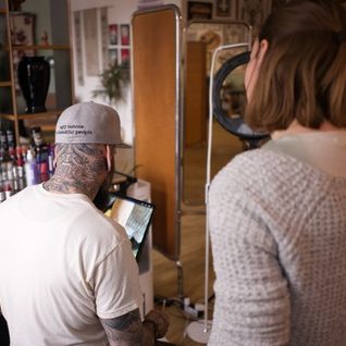 designing Eine tätowierte Hand zeichnet mit einem Pinsel auf Papier.marburg tattoo, tattoo marburg, tattoo studio marburg